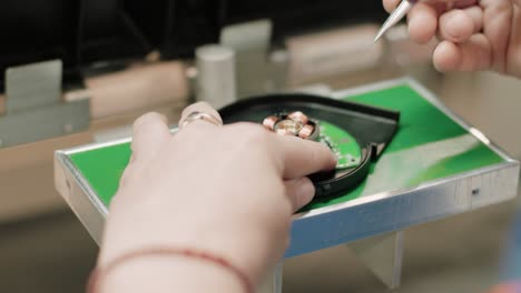 Person-working-on-a-microchip-in-a-factory-with-their-hands-close-up