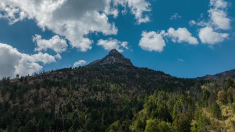 Hyperlapse-of-the-Nevado-de-Colima-peak-on-a-sunny,-cloudy-day,-with-sun-rays-illuminating-the-pine-woods