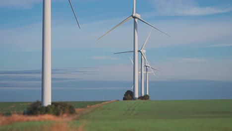 A-row-of-gigantic-wind-turbines-in-the-green-farm-fields