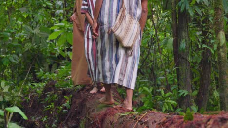 Indígenas-Descalzos-Caminando-Sobre-Un-Tronco-En-Oxapampa,-Perú,-Con-Vestimentas-Tradicionales,-Rodeados-De-Un-Frondoso-Bosque