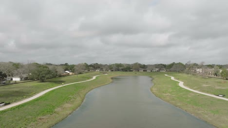 Una-Toma-Aérea-De-Seguimiento-Muestra-A-Un-Ciclista-De-Alto-Rango-Recorriendo-El-Espacio-Verde-De-Exploración-En-Un-Día-Nublado-En-Clear-Lake,-Houston,-Texas.