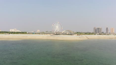 Rajkot-Atal-lake-drone-view-Many-birds-are-flying-in-drone-camera-and-big-lake-is-also-visible-and-big-giant-wheel-is-also-visible,-Rajkot-New-Race-Course,-Atal-Sarovar