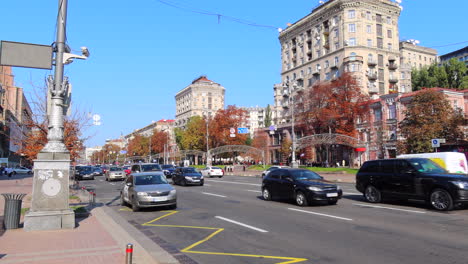 Khreshchatyk-main-street-of-Kyiv-city-capital-in-Ukraine,-sunny-weather-and-cars-driving,-tall-apartment-buildings,-4K-static-shot