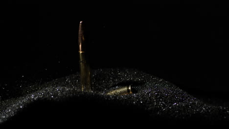 6mm-ARC-bullets-falling-into-gunpowder-dust-pile-in-slow-motion,-detail-closeup