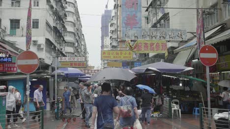 Der-Mong-Kok-Bereich-Des-Straßenmarkts-In-Hongkong-Ist-An-Einem-Regnerischen-Tag-Voller-Händler-Und-Fußgänger-Mit-Regenschirmen---Zeitlupe