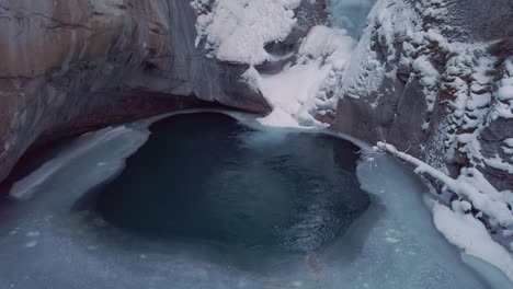 Frozen-waterfall-with-water-running-behind-ice-in-winter-tilt-up