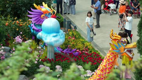 People-visiting-the-world-largest-glass-greenhouse,-Flower-Dome-at-Gardens-by-the-bay-during-Lunar-new-year-with-dragon-themed-sculptures-decoration-on-display-in-the-conservatory,-pan-up-shot
