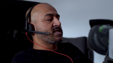 Asian-Indian-Working-From-Home-Having-Online-Conversation-Wearing-Headset-And-Swivelling-In-Chair