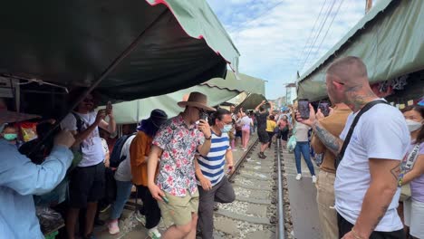 Turistas-Esperando-Que-El-Tren-Pase-El-Mercado-Ferroviario-De-Maeklong-Talad-Rom-Hub