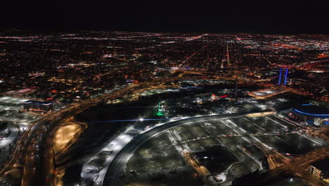 Downtown-Denver-i25-traffic-snowy-winter-evening-night-city-lights-landscape-aerial-drone-cinematic-anamorphic-highway-Colorado-Mile-High-DU-Metro-Eltiches-Empower-Field-Ball-Arena-circle-to-the-left