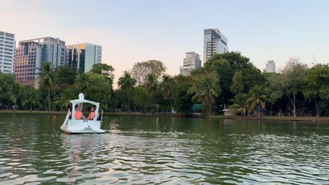 Couple-in-swan-paddle-boat-in-Lumpini-Park-Bangkok-lake-trees-and-nature