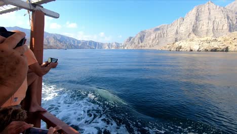The-view-of-the-waves-hitting-the-boat-in-the-Khasab-Sea,-tourists-taking-a-boat-tour-in-the-sea-and-taking-photos-with-their-phones