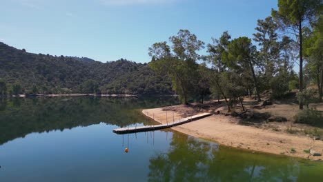 Idyllic-recreation-beach-on-Encinarejo-reservoir,-Sierra-de-Andujar-nature-reserve-AERIAL