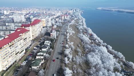 Scenic-Drive-On-Asphalt-Road-Through-Cityscape-And-Winter-Trees-By-The-Danube-River