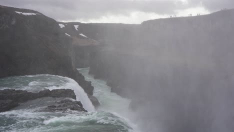 Misty-Gullfoss-Waterfall-in-Iceland-with-tourists-on-the-edge,-overcast-weather