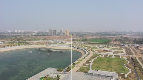 Rajkot-Atal-lake-drone-view-everything-is-looking-cool-and-the-camera-is-moving-downwards-lots-of-big-cars-and-lots-of-big-lakes-are-visible-around,-Rajkot-New-Race-Course,-Atal-Sarovar