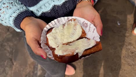 Toma-De-Paralaje-De-Una-Mujer-Sosteniendo-Una-Tostada-Malai-Servida-En-Un-Plato-De-Papel-En-Calcuta,-India.