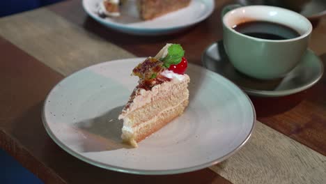 Dessert-decorated-with-cherry,-lemon-and-icing-sugar,-along-with-a-cup-of-coffee-served-on-a-wooden-table-in-the-cafe