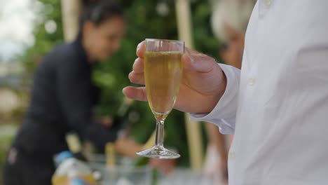 Langsame-Bokeh-Aufnahme-Eines-Mannes,-Der-Bei-Einer-Hochzeitsfeier-Ein-Glas-Champagner-Hält