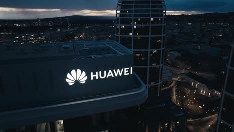 Aerial-drone-view-od-Huawei-logo-on-top-of-business-building-at-night---close-up