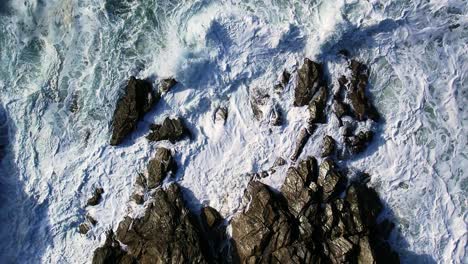 Aerial-Top-Down-of-White-Ocean-Waves-Over-Cornish-Rocks-in-Cornwall