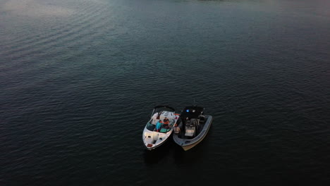 Aerial-view-of-police-or-guards-checking-motorboat-in-middle-of-lake-at-sunset