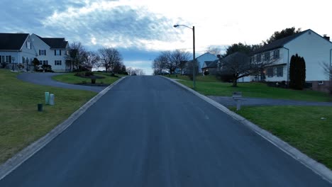 Drone-flyover-asphalt-road-in-hilly-american-neighborhood-at-dawn
