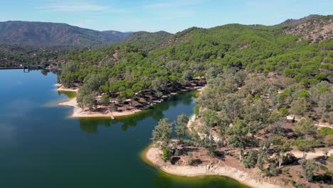Aerial-orbital-of-Encinarejo-lake-with-Sierra-de-Andujar-mountains-and-forests-landscape
