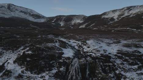 Aerial-shot-of-snow-dusted-mountains-and-Bride's-Veil-Waterfall-on-Skye,-Scotland