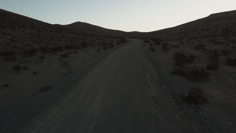 Aerial-footage-of-desert-dusty-road-leading-to-the-hills