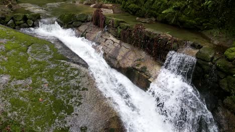 Grüner,-Moosbedeckter-Wasserfall-In-Einem-Waldgebiet