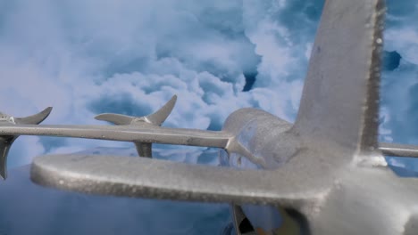 Makroobjektivansicht-Eines-Silbernen-Modellflugzeugs-Von-Hinten-Mit-Wolken-Im-Hintergrund-Und-Hereinziehendem-Video