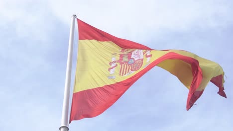 Detailaufnahme-Der-Spanischen-Flagge,-Die-In-Zeitlupe-Im-Wind-Weht,-Mit-Blauem-Himmel-Und-Wolken-Im-Hintergrund,-Nahaufnahme-Der-Spanischen-Flagge