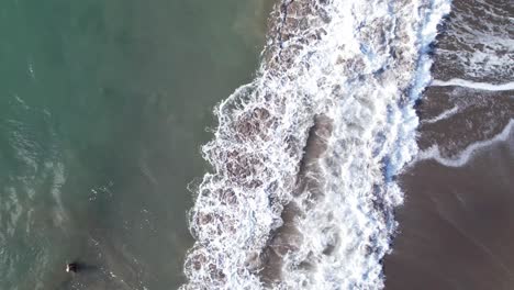 Aerial-view-of-person-in-water-being-pushed-by-waves