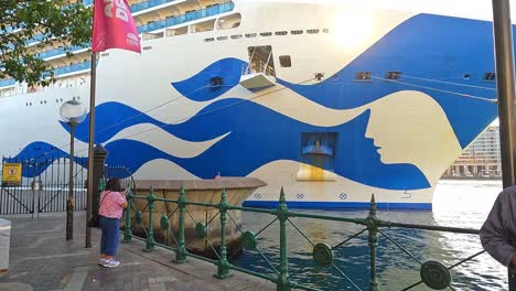 Sunlight-shining-through-bow-of-Cruise-ship-with-distinctive-blue-wave-design-docked-in-Sydney-Harbor,-bright-sunny-day