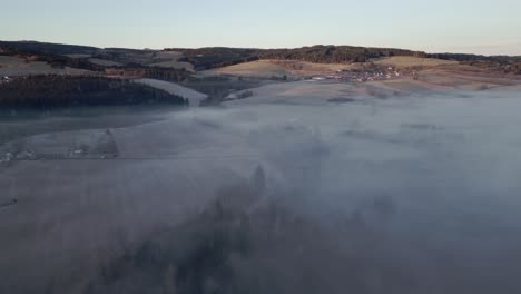 Eine-Luftaufnahme-Der-Nebelverhangenen-Sumava-Landschaft-Mit-Hügeln,-Wäldern-Und-Feldern,-Eine-Friedliche-Und-Natürliche-Szene