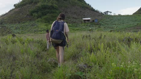 Tourist-following-local-people-in-the-rural-mountain-area-with-tall-grass-in-Cebu,-Philippines