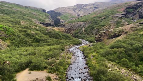 Tiny-mountain-river-flowing-through-rocky-valley-in-Iceland-on-misty-day