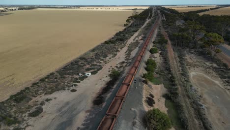 Long-train-transporting-iron-ore-across-the-desert-in-Esperance,-Western-Australia,-aerial-dynamic