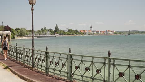 Woman-Walking-Overlooking-Lake-Constance-Bodensee-with-View-of-Friedrichshafen,-Germany