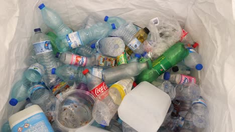Draufsicht-Auf-Plastikflaschen,-Die-In-Recyclingbehälter-Geworfen-Werden,-Zeitraffer