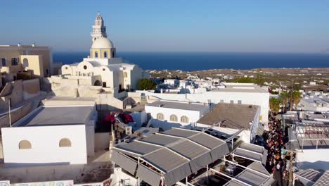 Aerial-over-Cable-Car-Station-and-Catholic-Cathedral-in-Fira,-Santorini,-Greece