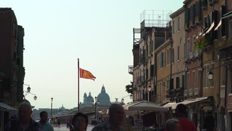 Szenen-Entfalten-Sich-Entlang-Der-Straßen-Von-Venedig,-Wimmelt-Es-Von-Touristen,-Vor-Dem-Hintergrund-Der-Venezianischen-Flagge,-St