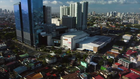 Aerial-view-approaching-the-Ayala-Malls-Circuit,-afternoon-in-Manila,-Philippines