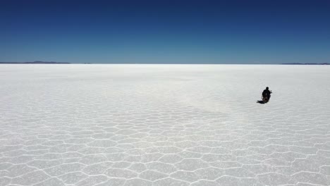 Motorradfahrer-Fährt-Auf-Dem-Salzsee-Von-Uyuni,-Bolivien,-In-Richtung-Des-Fernen-Flachen-Horizonts