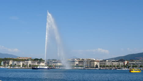 Boats-sailing-under-Geneva-Jet-d'eau-water-fountain-on-the-Swiss-Lac-Leman-lake-waterfront