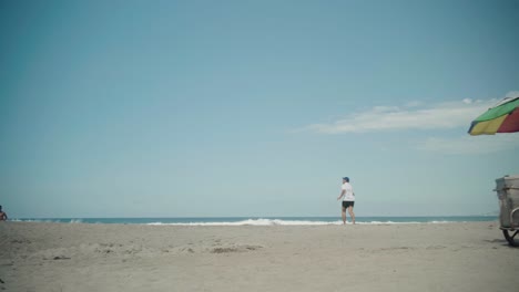 Mann-Zieht-Einen-Eisstand-Mit-Buntem-Sonnenschirm-Am-La-Union-Beach,-Philippinen