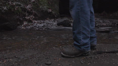 close-up-of-a-hikers-boots-as-he-approaches-a-stream-where-he-reaches-into-his-backpack-to-retrieve-a-tin-cup-to-get-water-from-the-creek