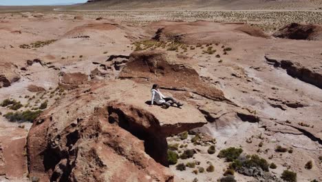 órbitas-Aéreas-Mujer-En-Alta-Roca-Chapitel-En-El-árido-Altiplano,-Bolivia