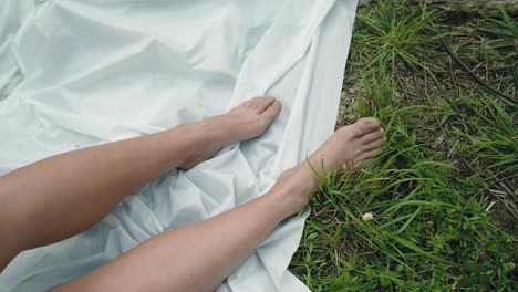 Woman-Bare-feet-graze-linen-amidst-whispers-of-green
